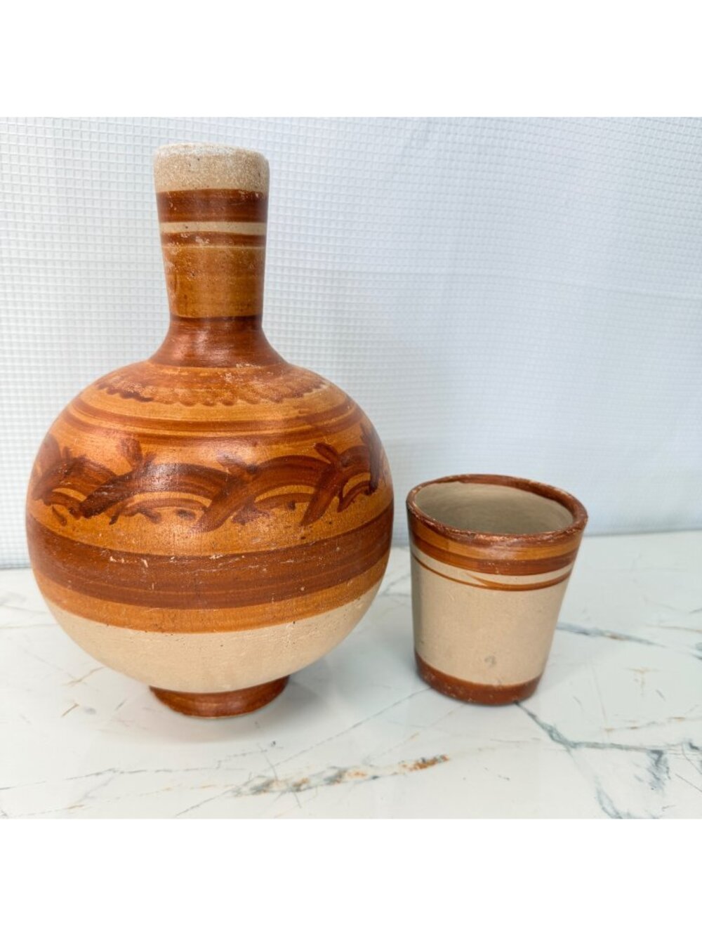 Traditional Mexican artisanal terracotta water jug with a matching cup, featurin